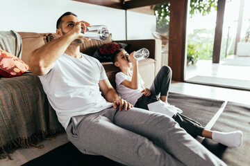 Latin father and son rest after exercising at home