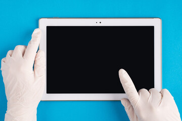 Medicine and technology concept. Top above overhead pov first person view photo of therapist physician in latex white gloves using tablet to track patient's health isolated on blue background