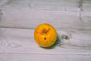 Yellow autumn organic apple autumn fruit with red stainds isolated on a grey wooden textured background