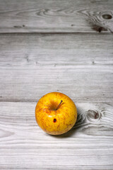 Yellow autumn organic apple autumn fruit with red stainds isolated on a grey wooden textured background
