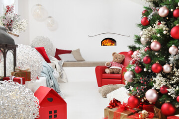 Fototapeta na wymiar merry christmas, white comfortable modern home living room with tree, decorations and gift packages, teddy bear on red armchair near the sofa full of cushions and with the fireplace on the wall
