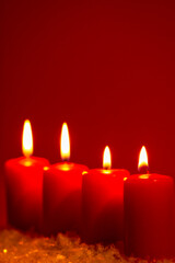 Four burning candles on snow dark red background