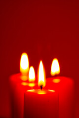Four burning candles on snow dark red background