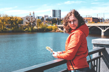 Girl on the river in spring. Woman holds a flower