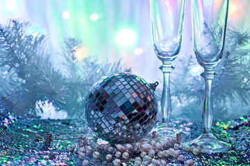 Whineglasses with disco ball and pearl beads on a colorful background. New year celebration concept.