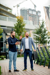 Young businessmen standing  with tablet and discussing about plans for the future of the company 