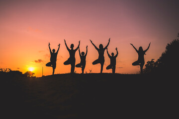 Fototapeta na wymiar silhouette of people doing beach yoga in the sunrise