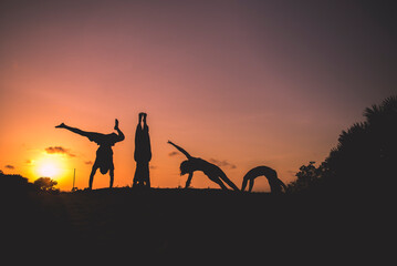 silhouette of people doing beach yoga in the sunrise