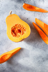 Fresh butternut squash on the grey background. Butternut Pumpkin. Halves of raw orange pumpkin. Contrast photo. Healthy Meal Prep, recipe preparation photo. Seasonal pumpkin cooking