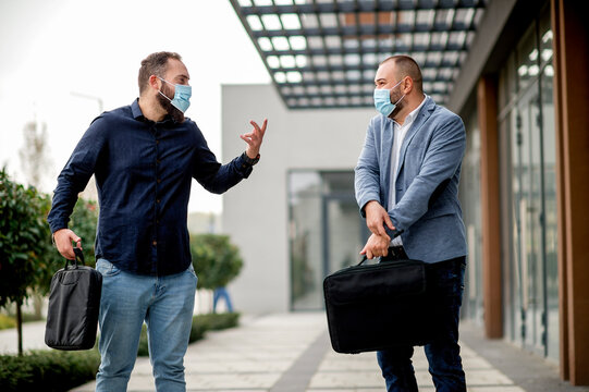 Two Business People Wearing Protective Face Masks And Talking To Each Outdoors