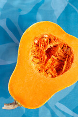 Fresh butternut squash on the blue background. Butternut Pumpkin. Halves of raw orange pumpkin. Contrast photo. Healthy Meal Prep, recipe preparation photo. Seasonal pumpkin cooking