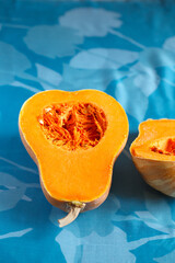 Fresh butternut squash on the blue background. Butternut Pumpkin. Halves of raw orange pumpkin. Contrast photo. Healthy Meal Prep, recipe preparation photo. Seasonal pumpkin cooking
