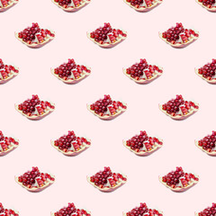 Bright red pomergranate pieces repeat seamless pattern on light pink background.