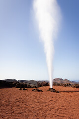 Artificial volcanic vapor geyser ejecting water in Timanfaya National Park, Lanzarote. Tourism attraction, travel destination concepts