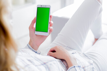 woman is relaxing on comfortable couch and using smartphone at home