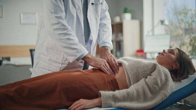 Doctor Consultation Office: Female Patient Lying on a Bed while Family Physician Checks Her Abdomen. Medical Health Care Specialist Localizes Stomach Pain, Identifying Disease, Prescribing Treatment 