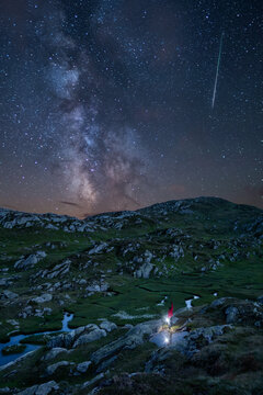 Man holding lantern standing under a starry sky