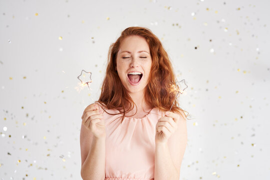 Portrait of shouting young woman with two sparklers
