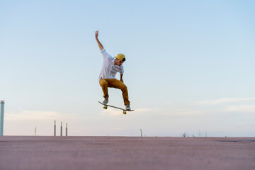 Young man doing a skateboard trick on a lane at dusk