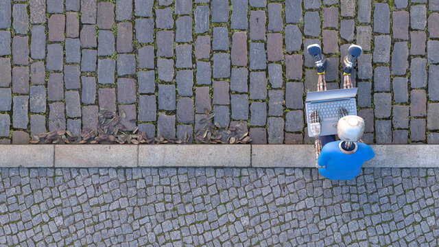 Robot sitting on curb using laptop, 3d rendering
