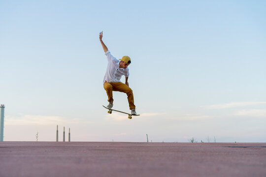 Young man doing a skateboard trick on a lane at dusk - Powered by Adobe