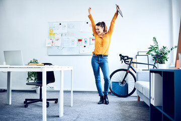 Happy young businesswoman cheering in office