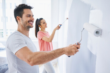 Happy couple painting wall in apartment together