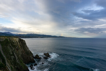 jagged and rocky ocean coast with cliffs and a rainbow