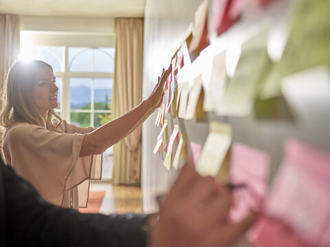 Colleagues Collecting Ideas On Sticky Notes At The Wall