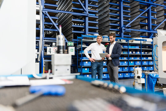 Businessmen using tablet during meeting in production hall