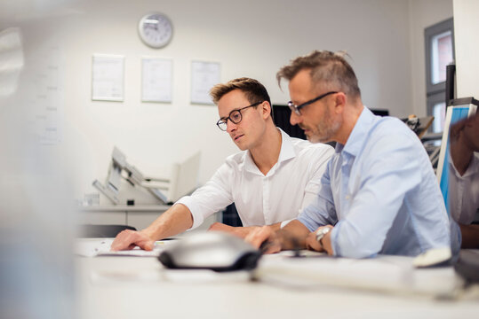 Two businessmen discussing plan on desk in office