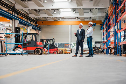 Two men wearing hard hats in factory shop floor
