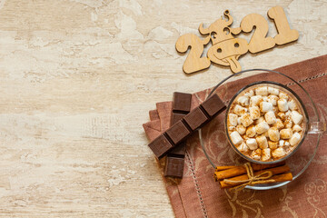 Cup of hot chocolate with marshmallows, cinnamon and anise on wooden background.