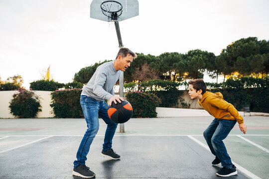 Father and son playing basketball on an outdoor court