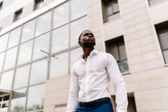 Confident businessman looking away while standing against office building in city
