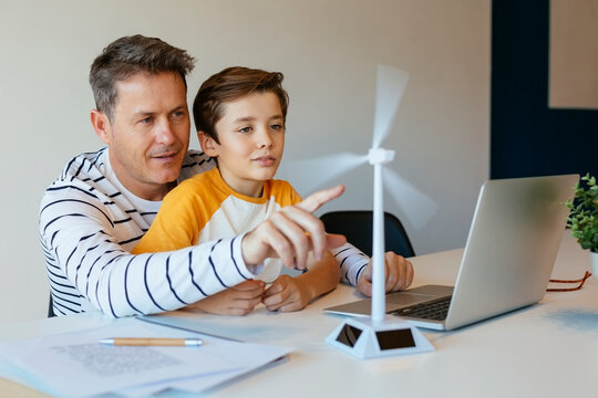 Father and son with laptop testing wind turbine model