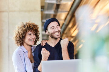 Excited man and woman with laptop in modern office