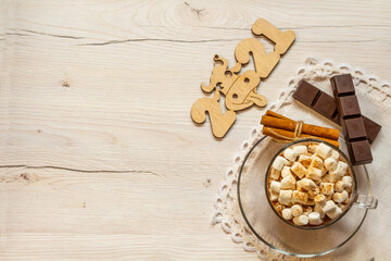 Cup of hot chocolate with marshmallows, cinnamon and anise on wooden background.