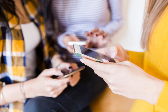 Hands of three women using smartphones