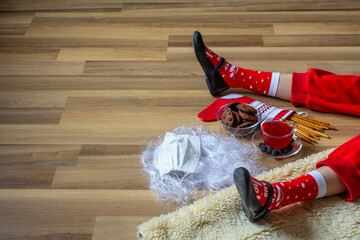 Santa hat, mittens and beard with medical mask on wooden background