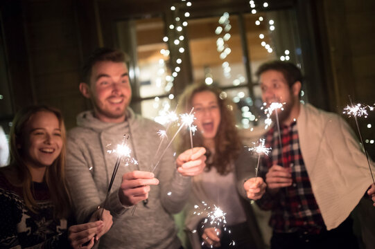 Happy friends holding sparklers outdoors at night