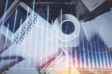 Double exposure of financial graph hologram over desktop with phone. Top view. Mobile trade platform concept.