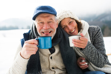 Portrait of senior couple with hot beverages in winter