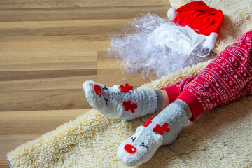 Santa hat, mittens and beard with medical mask on wooden background