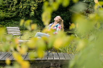 Young woman relaxing on jetty in garden