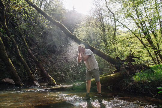 Young man washing his face at lakeshore