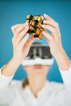Businesswoman wearing VR glasses holding cubical structure