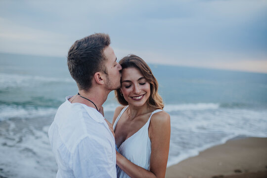 Man kissing woman while standing at beach