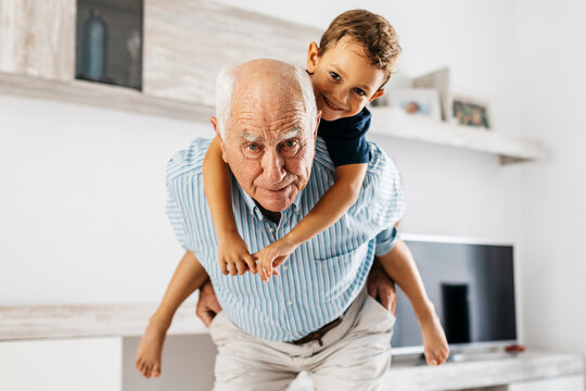 Portrait of grandfather giving his grandson a piggyback ride in the living room