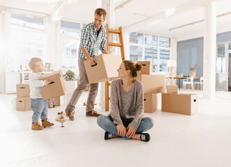 Happy family moving into new home with father and daughter carrying cardboard boxes